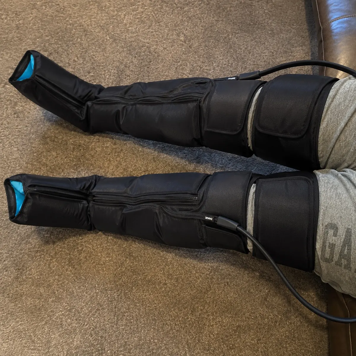 Tim wearing black pneumatic compression recovery boots at home
